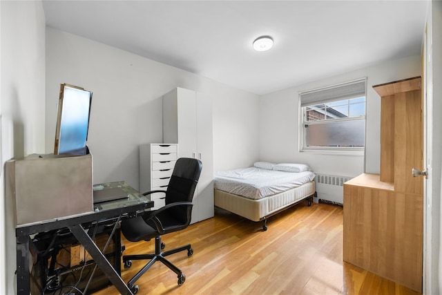 bedroom with radiator heating unit and light wood-style floors