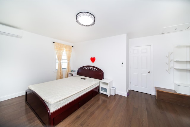 bedroom with a wall mounted air conditioner, baseboards, and dark wood-type flooring