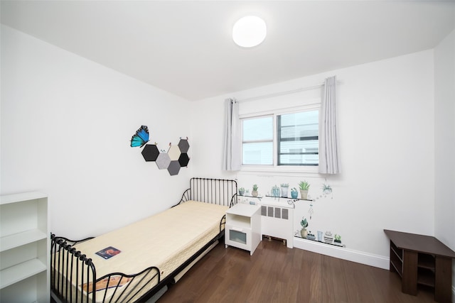 bedroom featuring baseboards, dark wood-type flooring, and radiator heating unit