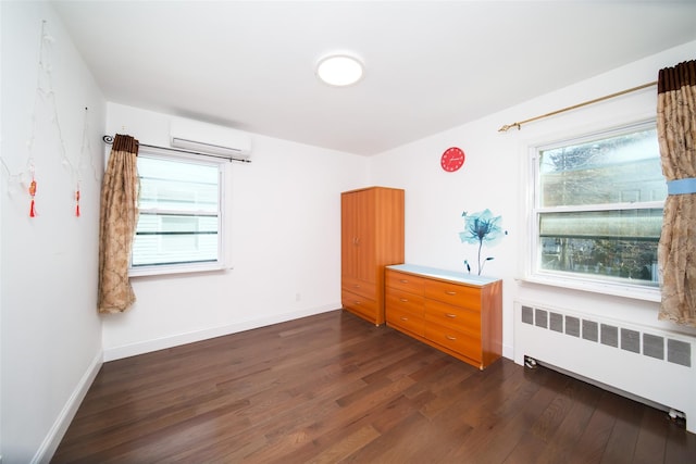 empty room with a wealth of natural light, radiator, dark wood-style floors, and a wall unit AC