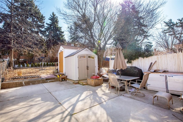 view of patio featuring a fenced backyard, a shed, outdoor dining space, and an outdoor structure