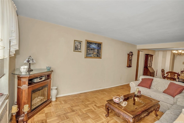 living area with a notable chandelier, a glass covered fireplace, radiator, and baseboards