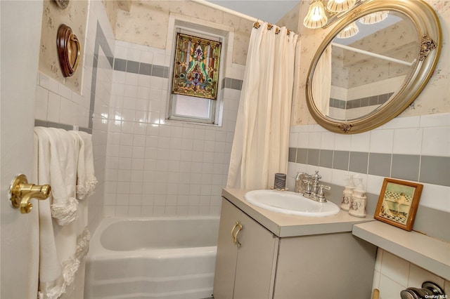 bathroom with wallpapered walls, shower / bath combination with curtain, and wainscoting