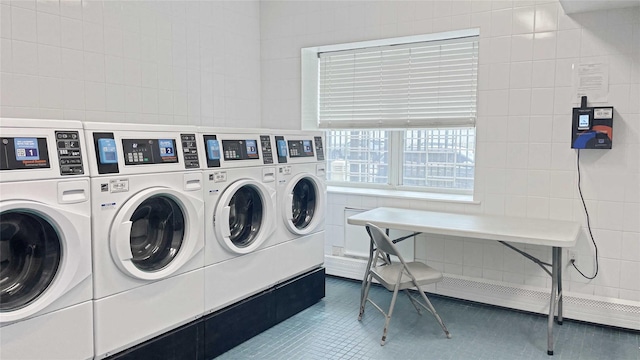 shared laundry area with tile patterned flooring, tile walls, baseboard heating, and washing machine and clothes dryer