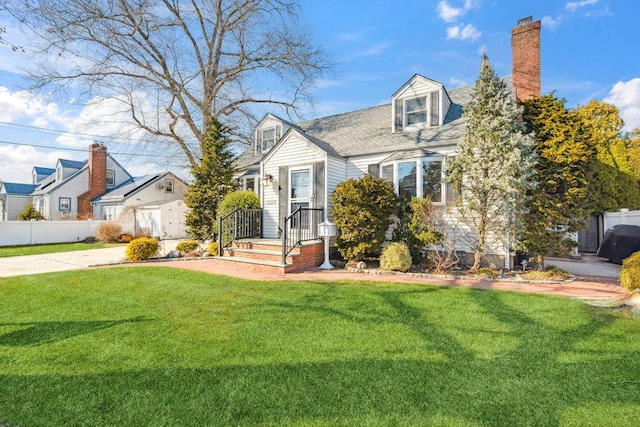 cape cod home with a shingled roof, a chimney, a front yard, and fence