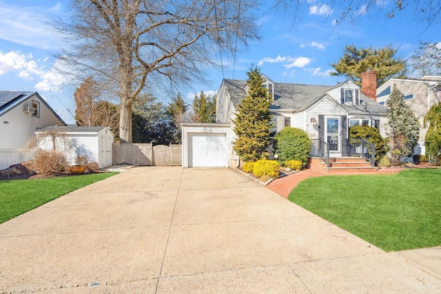 cape cod-style house featuring a storage unit, driveway, fence, a front yard, and an attached garage