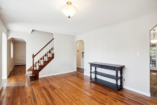 interior space featuring stairway, arched walkways, baseboards, and wood finished floors