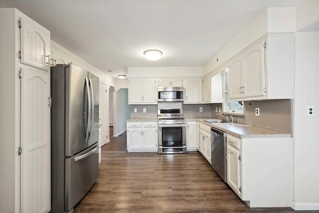 kitchen featuring a sink, light countertops, dark wood-type flooring, appliances with stainless steel finishes, and white cabinetry