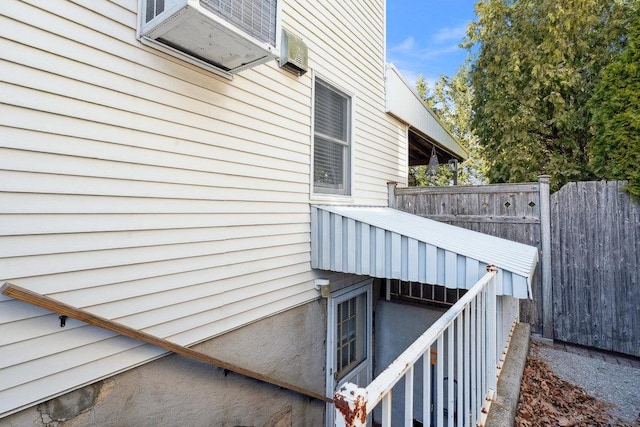 exterior space featuring a wall unit AC and fence