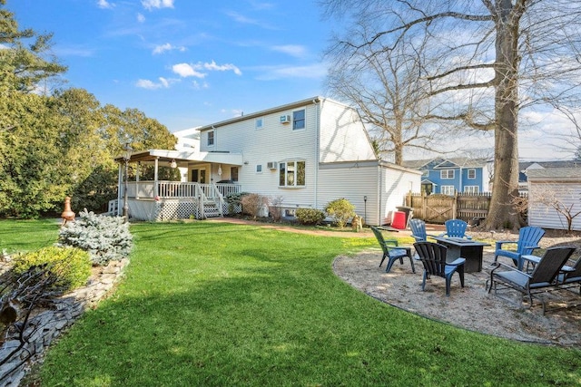 rear view of house featuring fence, a fire pit, a deck, a patio area, and a lawn