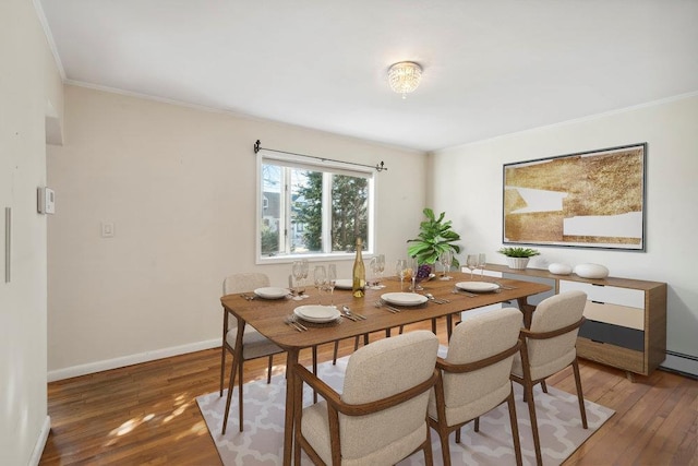 dining space with baseboards, wood-type flooring, and ornamental molding