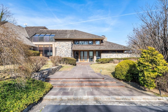 view of front of property with a chimney and stone siding