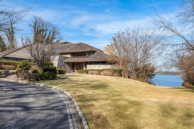 view of front of house featuring a chimney, a front yard, and a water view