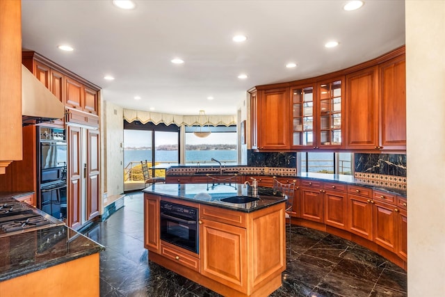 kitchen featuring recessed lighting, a sink, brown cabinetry, and a kitchen island