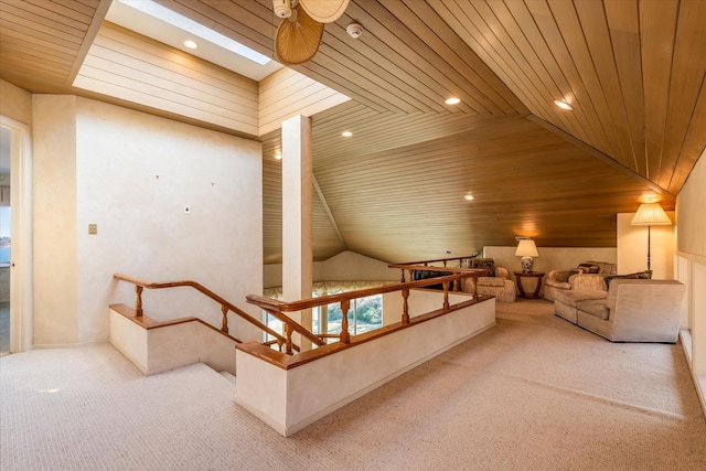 carpeted living room featuring a skylight, ceiling fan, wood ceiling, and recessed lighting