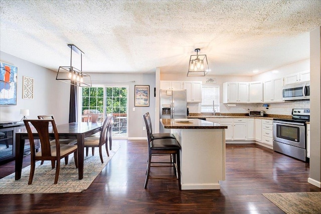 10 Lyford Ln, Poughkeepsie, NY 12601 - kitchen featuring stainless steel appliances, a center island, dark wood finished floors, white cabinets, and a textured ceiling