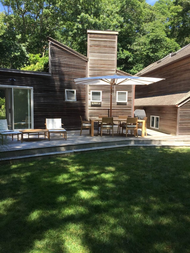 rear view of property featuring a yard, a deck, and a chimney