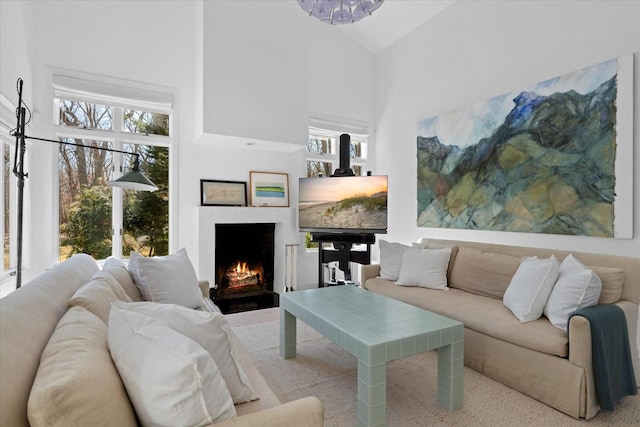 living room with high vaulted ceiling and a lit fireplace