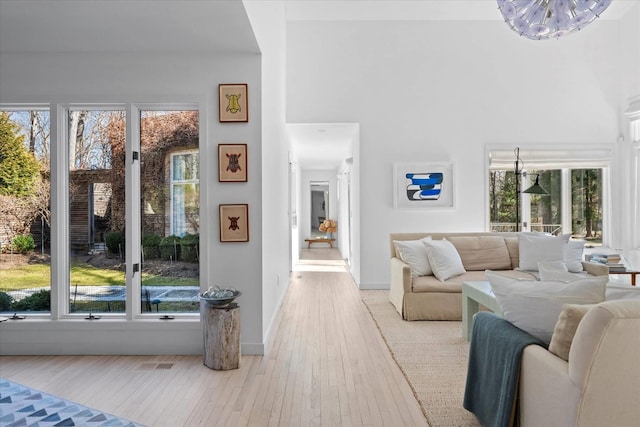 living area featuring a high ceiling, baseboards, visible vents, and wood-type flooring