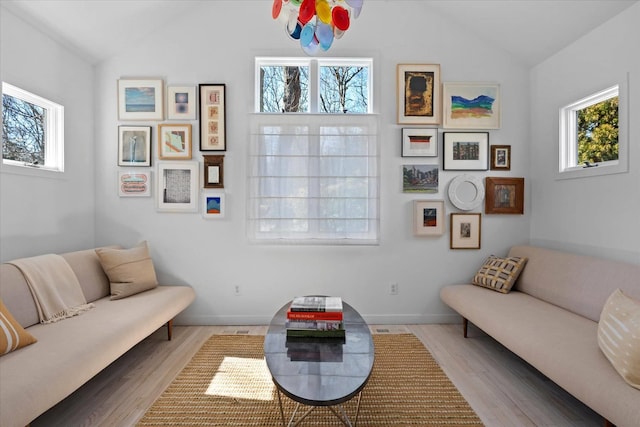 living room with lofted ceiling, baseboards, and light wood finished floors