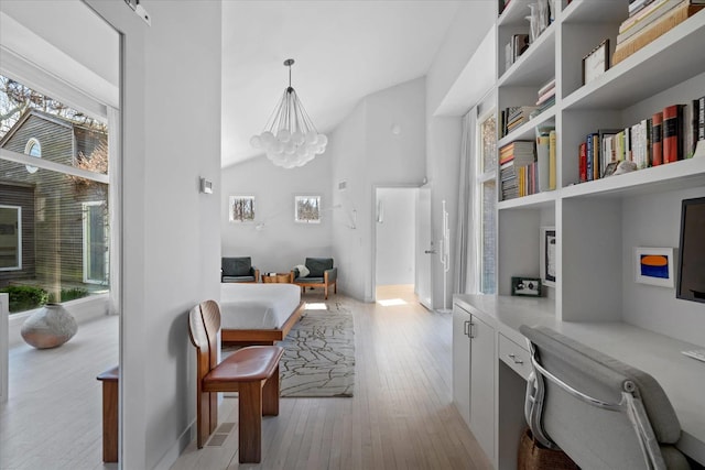 interior space with high vaulted ceiling, a notable chandelier, light wood-style floors, and built in desk