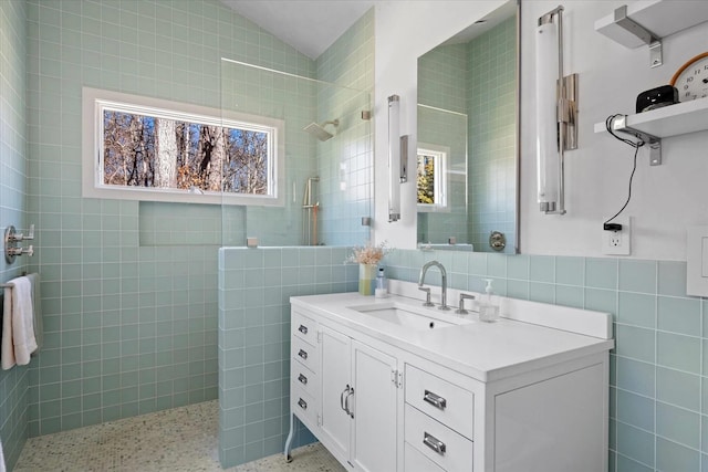 full bathroom featuring tile walls, speckled floor, walk in shower, vanity, and vaulted ceiling