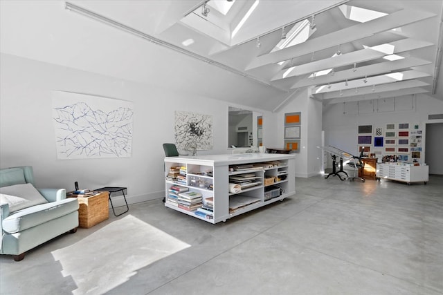 misc room with a skylight, finished concrete flooring, baseboards, and high vaulted ceiling