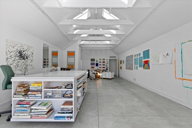 miscellaneous room featuring lofted ceiling with skylight, baseboards, and concrete floors