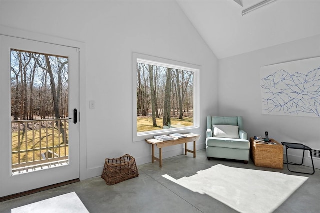 sitting room with baseboards, high vaulted ceiling, and finished concrete floors