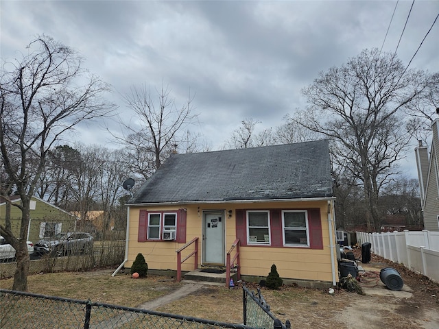 bungalow-style home with cooling unit and a fenced front yard