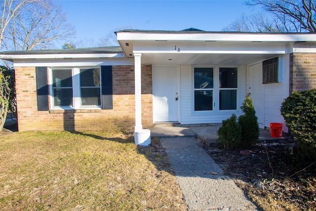 view of front of house featuring brick siding, a porch, and a front yard