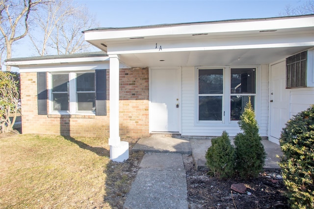 entrance to property featuring a yard and brick siding