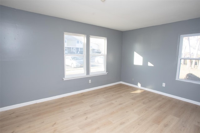 unfurnished room with baseboards and light wood-style flooring