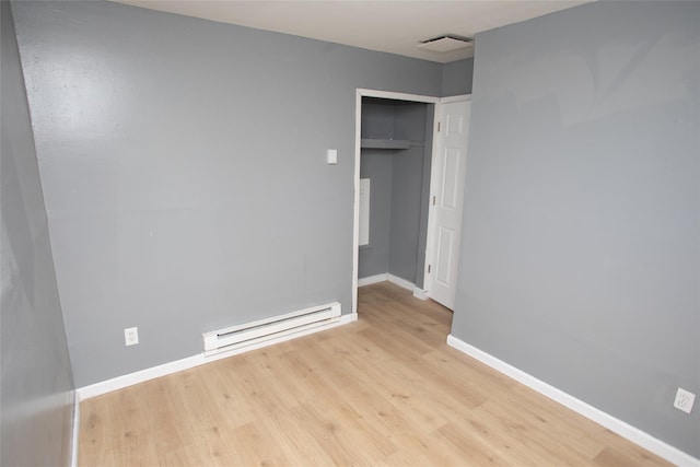 unfurnished bedroom with light wood finished floors, visible vents, baseboards, a closet, and a baseboard radiator