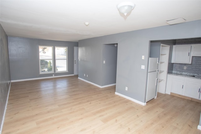 unfurnished living room featuring light wood-style flooring and baseboards