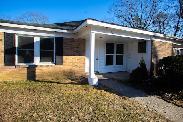 exterior space featuring brick siding and a lawn