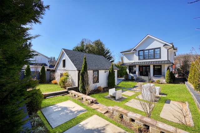 back of property featuring metal roof, a lawn, board and batten siding, and a standing seam roof