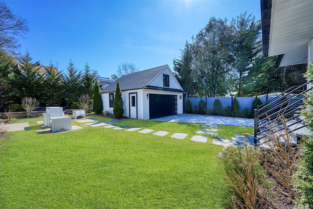 view of yard featuring an outbuilding, a detached garage, and fence