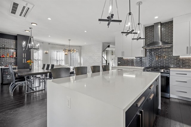 kitchen featuring visible vents, stainless steel range oven, light countertops, wall chimney exhaust hood, and dark wood-style flooring