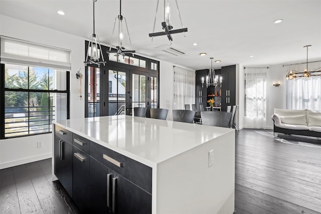 kitchen with open floor plan, dark cabinetry, a healthy amount of sunlight, and a chandelier