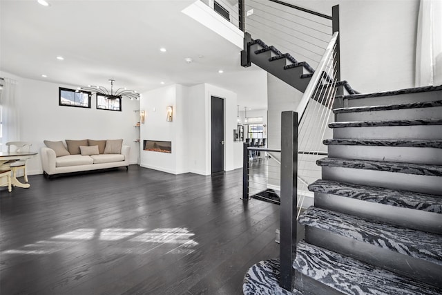 stairway featuring a glass covered fireplace, recessed lighting, wood finished floors, and baseboards