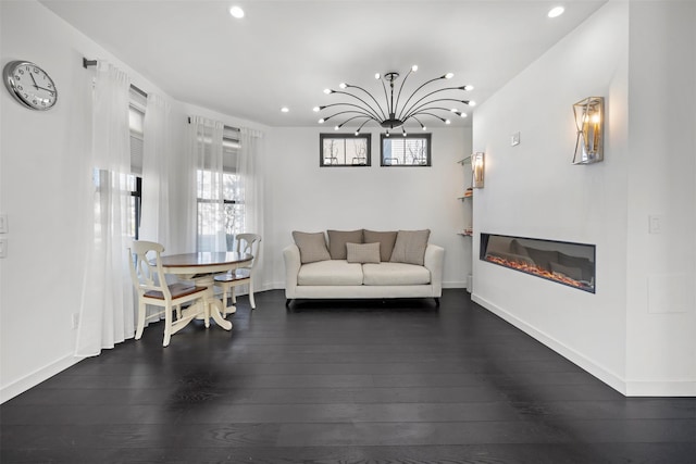 living area with a wealth of natural light, a glass covered fireplace, and hardwood / wood-style floors