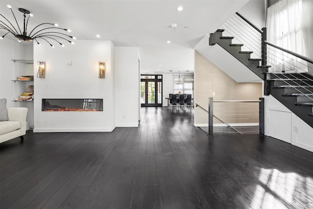 unfurnished living room featuring hardwood / wood-style floors, an inviting chandelier, a glass covered fireplace, and recessed lighting