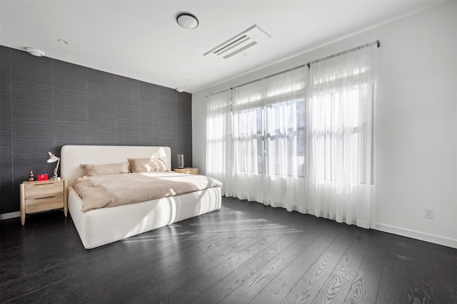 bedroom with visible vents, baseboards, and dark wood-style flooring