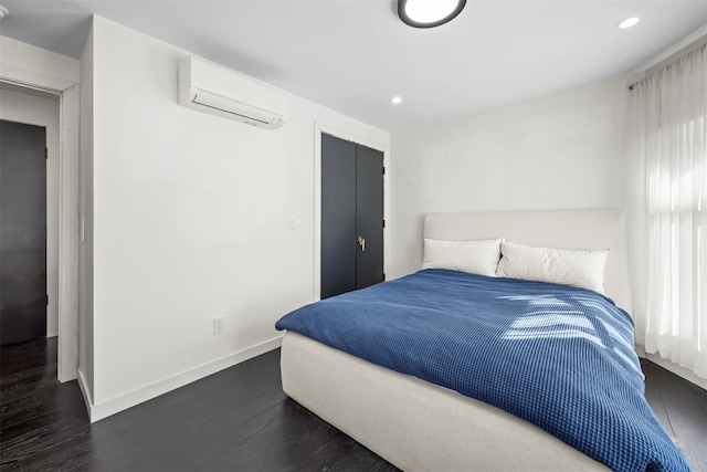 bedroom featuring a wall unit AC, recessed lighting, baseboards, and dark wood-style flooring