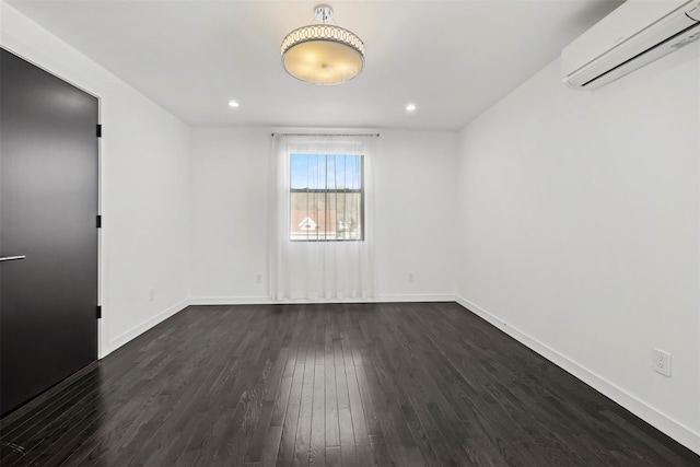 empty room featuring dark wood-style floors, recessed lighting, an AC wall unit, and baseboards