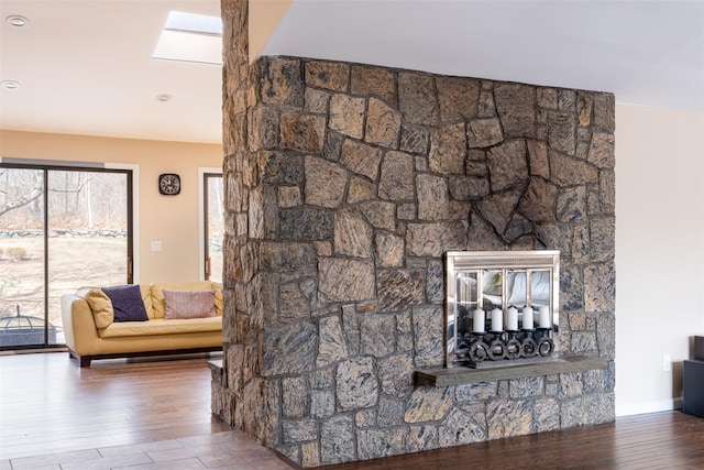 room details featuring a fireplace, a skylight, wood finished floors, and baseboards