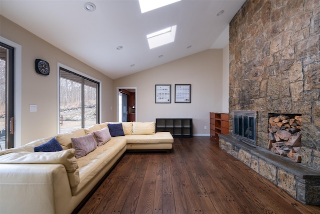 living area featuring hardwood / wood-style floors, lofted ceiling with skylight, a fireplace, and baseboards