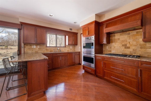 kitchen featuring brown cabinets, a kitchen breakfast bar, appliances with stainless steel finishes, a peninsula, and a sink