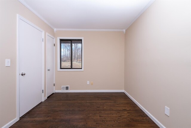 spare room featuring visible vents, ornamental molding, baseboards, and dark wood-style flooring